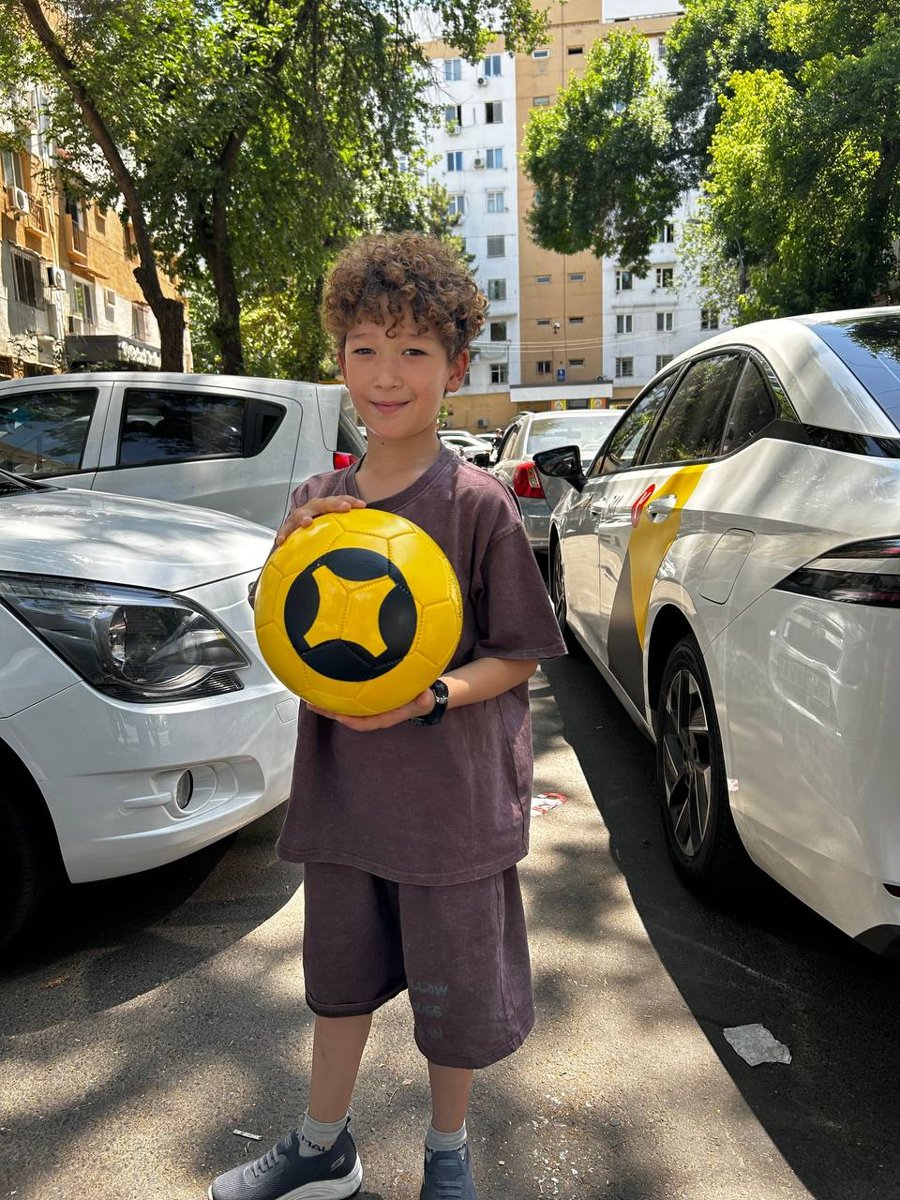 A boy holding the yellow Yandex ball next to the cars